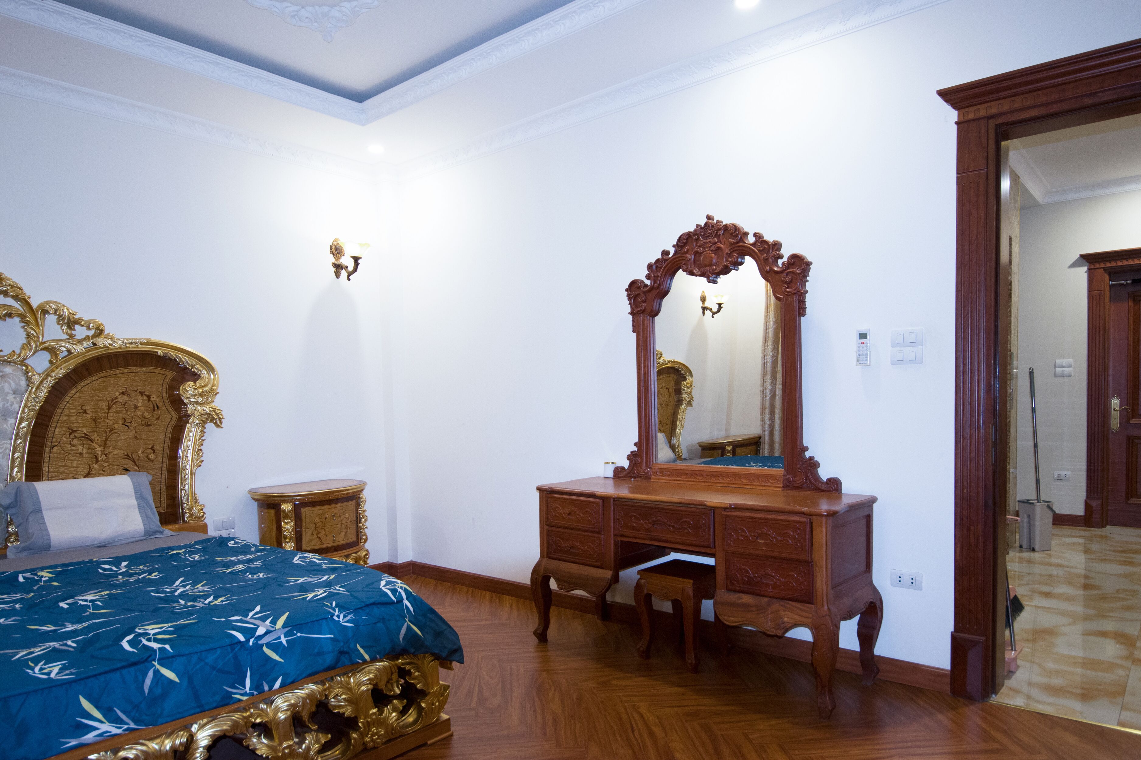 A bedroom with a bed, a dresser, a mirror, and a door leading to another room.