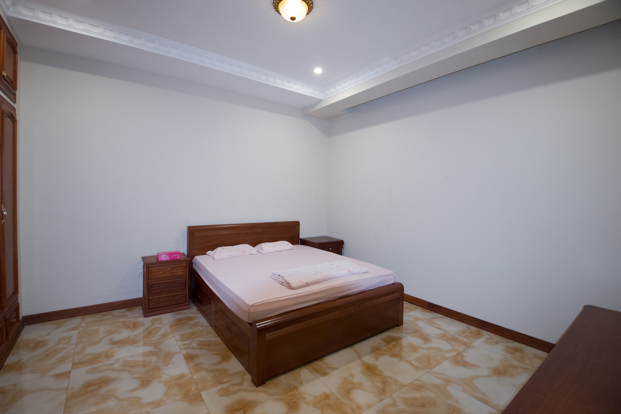 A bedroom with a wooden bed, a nightstand, and a wardrobe.