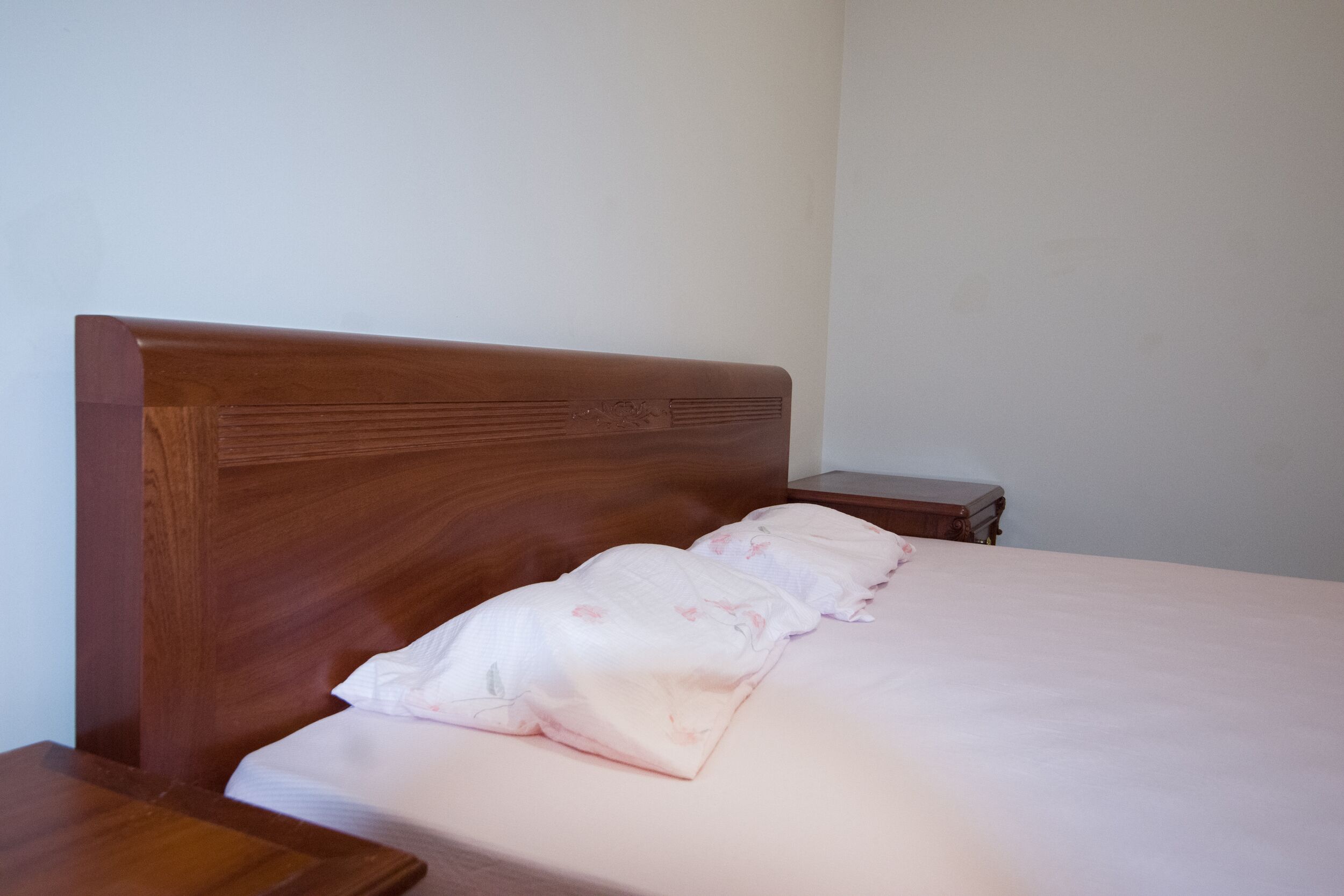 A single bed with a wooden headboard, a bedside table, and a nightstand.