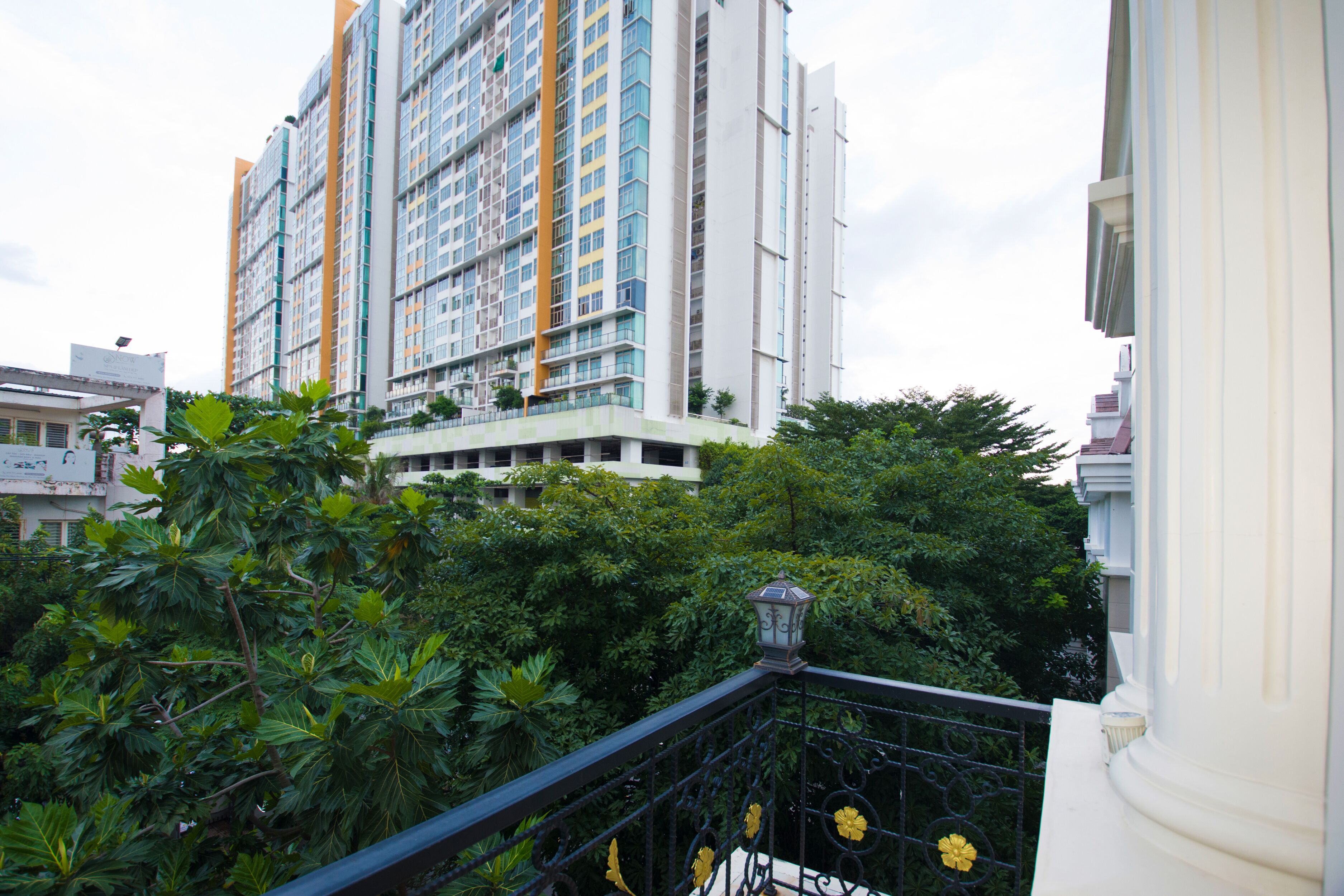 A high-rise building with multiple balconies and a lush green garden in the foreground.