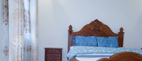 Une chambre à coucher avec un lit en bois, une table de chevet et une lampe fixée au mur.