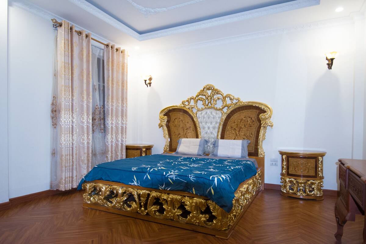 Ein Schlafzimmer mit einem großen, verzierten Bett, Holzboden und zwei Nachttischen.
