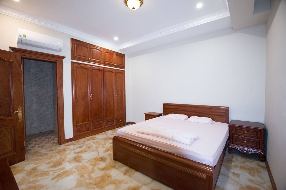 Ein Schlafzimmer mit einem großen Bett, einem Holzschrank und einem kleinen Nachttisch.