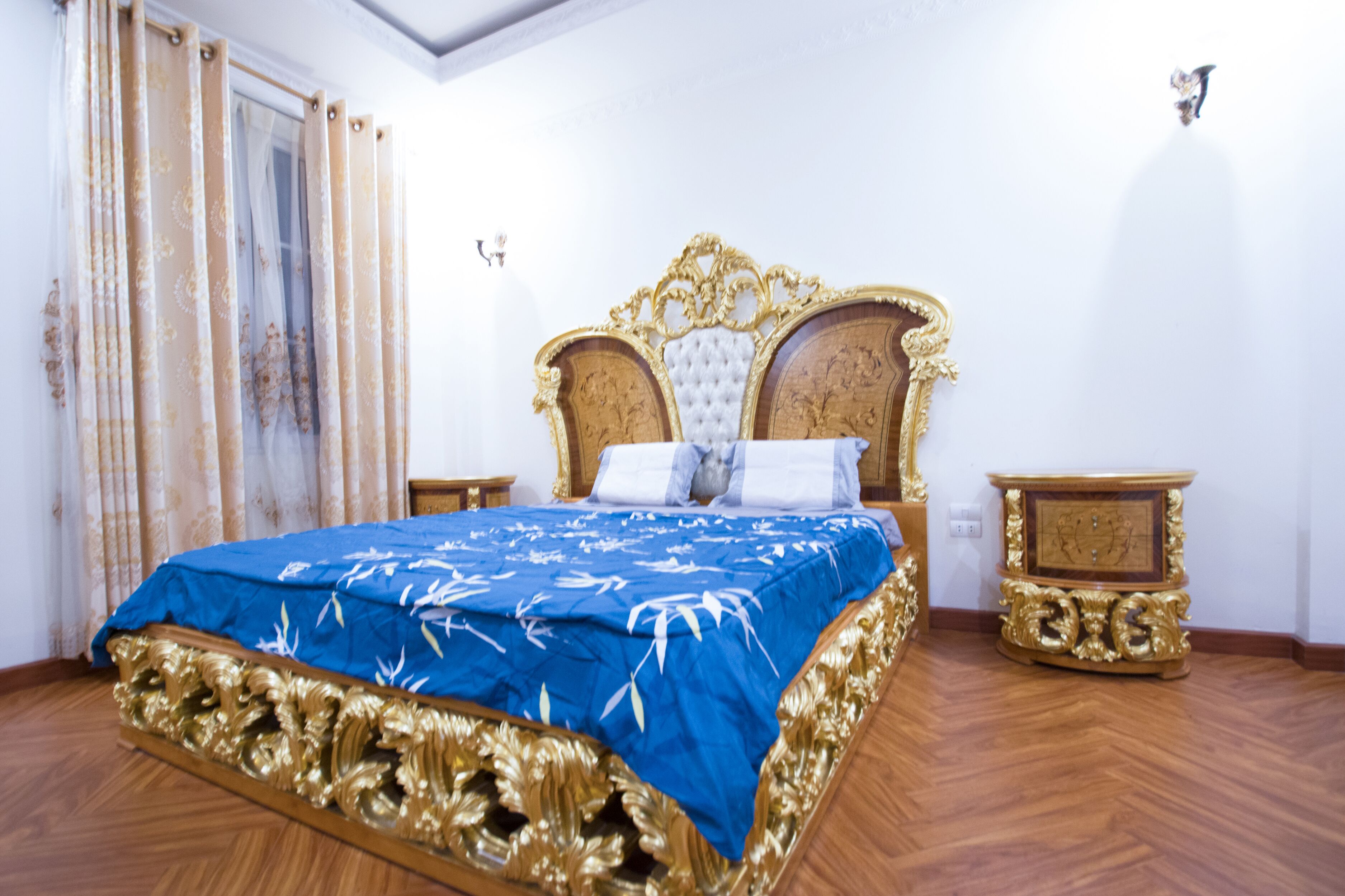 A bedroom with a large bed, ornate headboard, and matching nightstands.