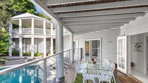 A covered outdoor area with a pool, a glass table, and white chairs. - Tropical Family Hideaway, Noosa Heads (Noosa Heads)