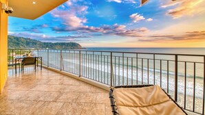 Un balcon avec vue sur la mer et sur le coucher du soleil.