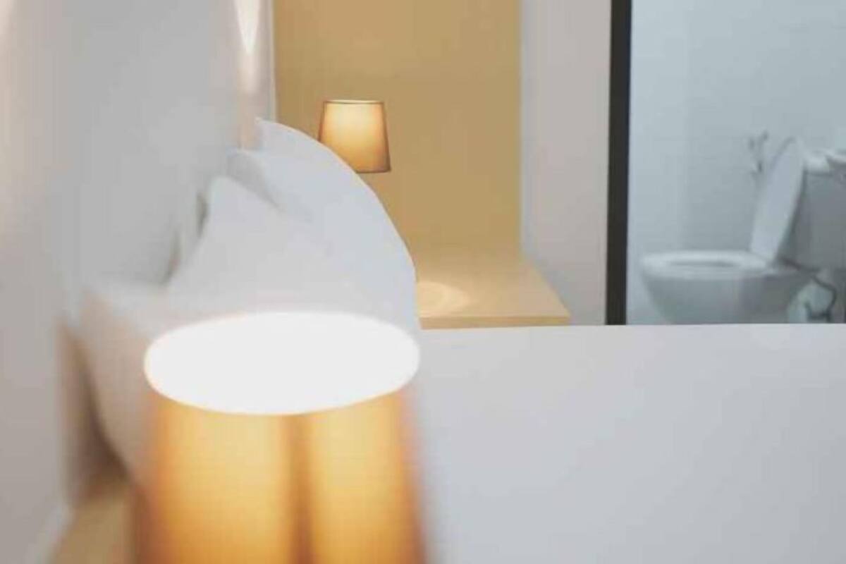 A modern bathroom with a white sink, a mirror, and a wall-mounted light fixture.