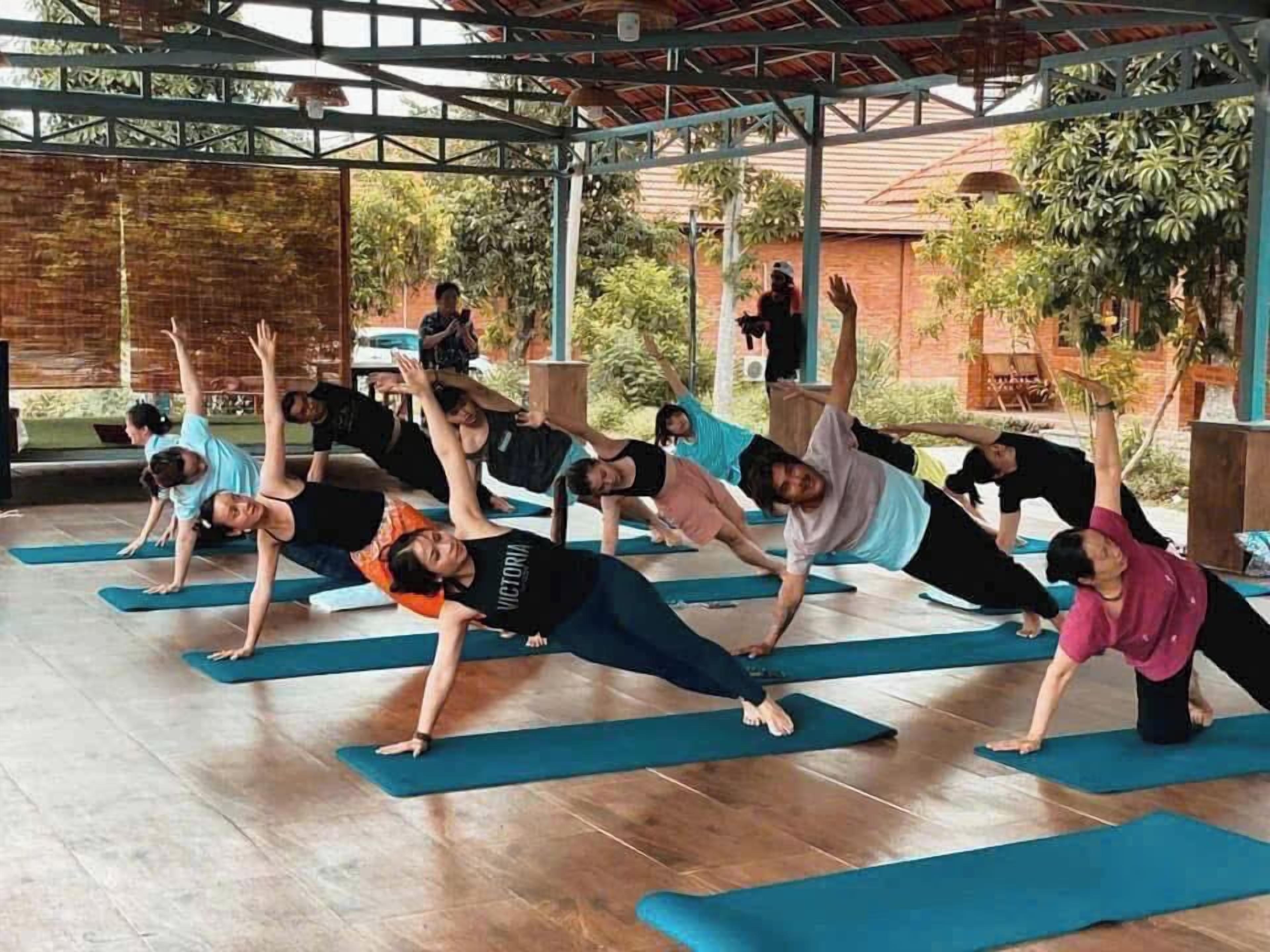 A group of people performing a yoga exercise outdoors on mats.