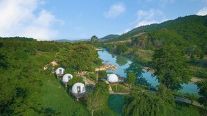 A series of dome-shaped accommodations surrounded by lush greenery and a river. - Orchard Home Resort Nam Cat Tien (Nam Cat Tien)