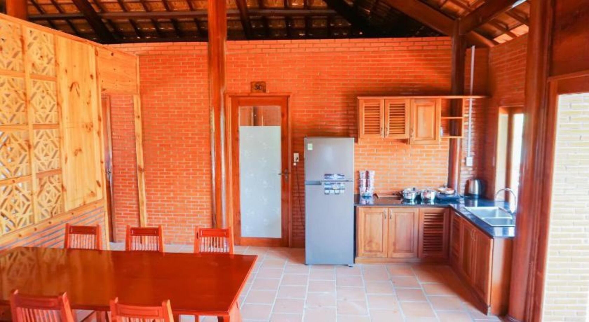 Una cocina rústica con paredes de ladrillo, armarios de madera y piso de baldosas.