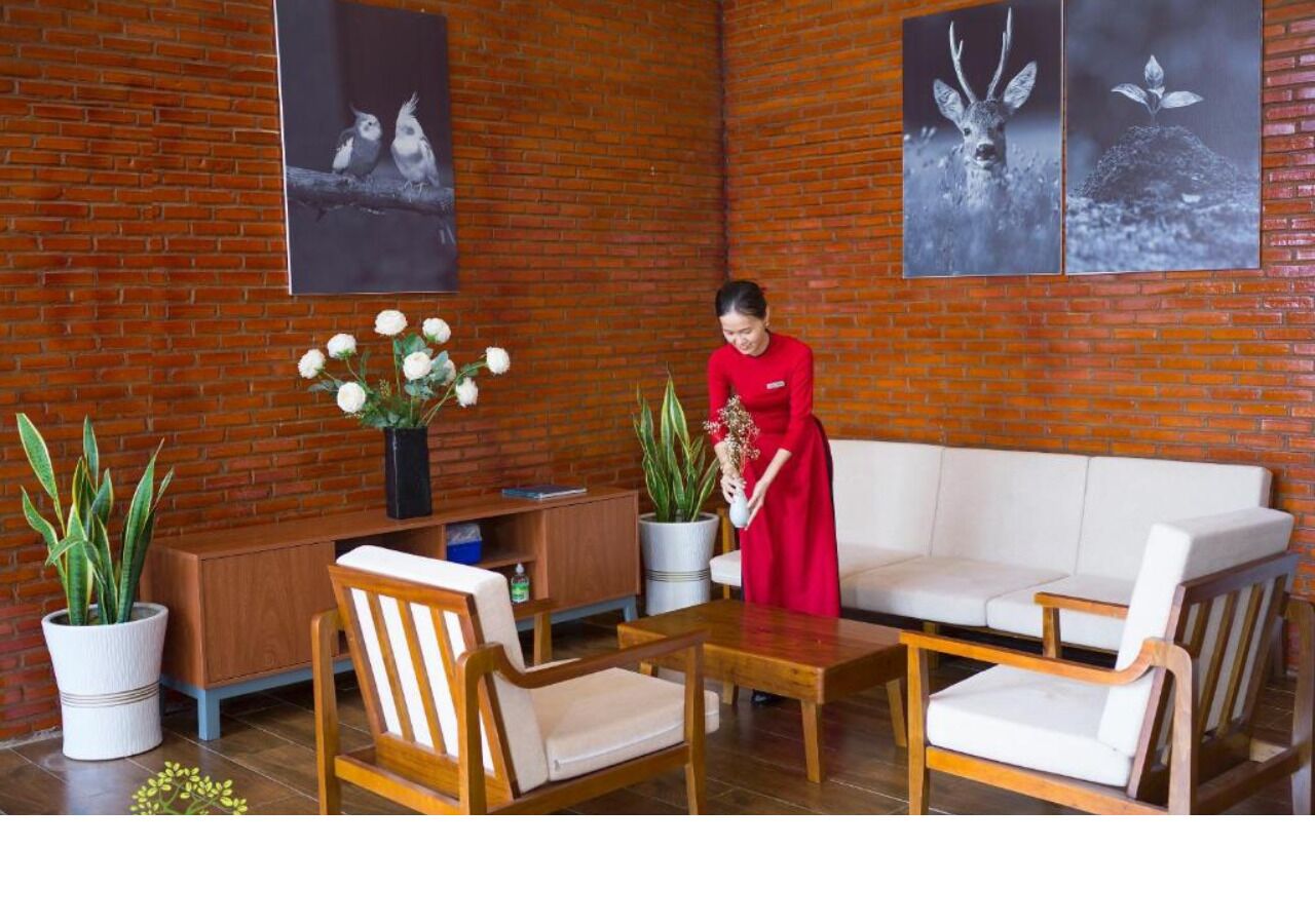 A room with a brick wall, a sofa, two chairs, a table, and a potted plant.