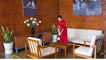 A room with a brick wall, a sofa, two chairs, a table, and a potted plant.