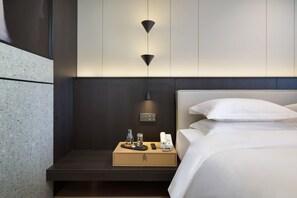 A modern hotel room with a neatly made bed, a bedside table with a lamp, a phone, and a small tray with a vase and candle. - Guilin Mingjiang Hotel (Guilin)