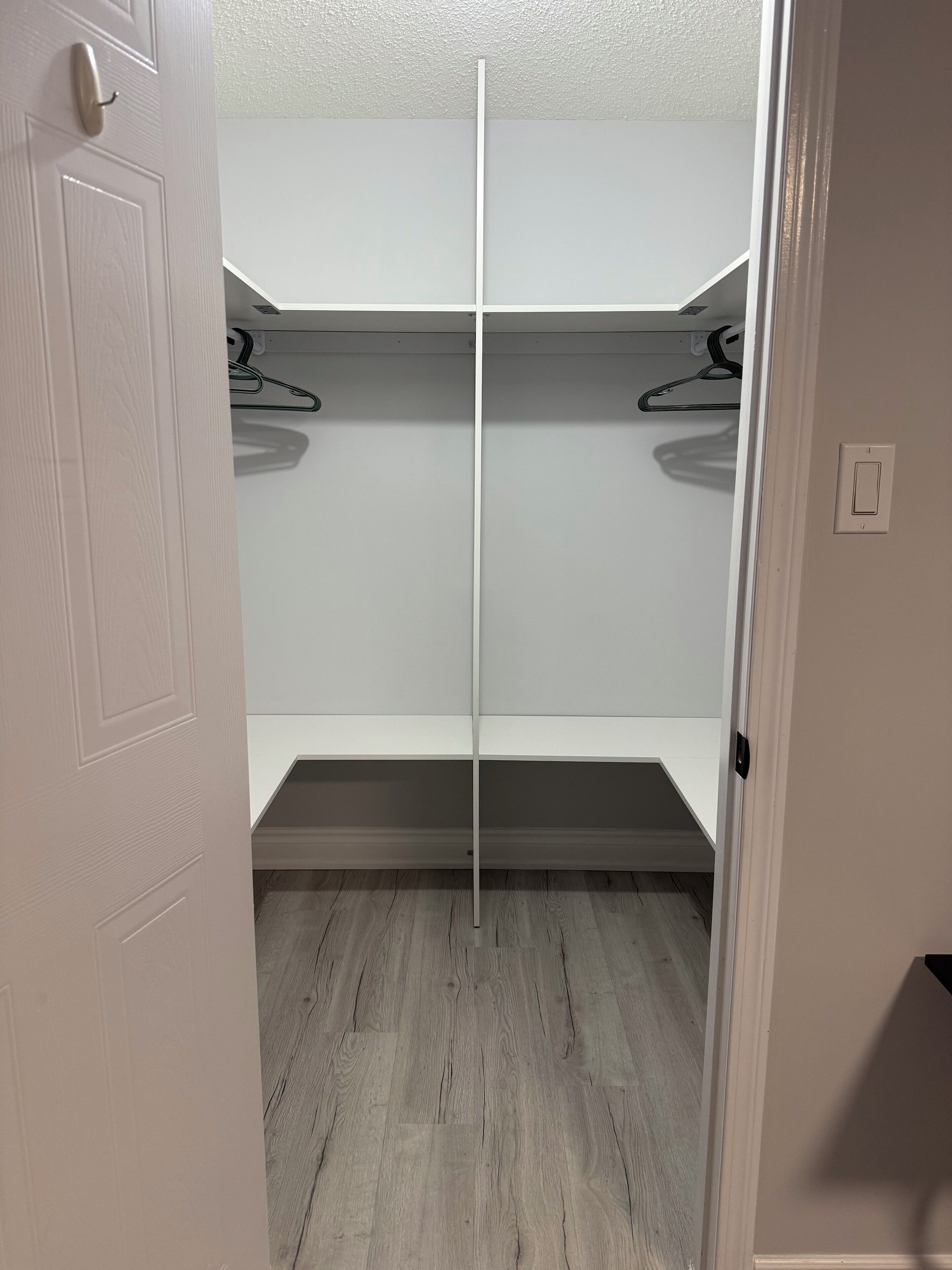 Un dressing avec des étagères blanches et un plancher en bois.