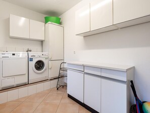 A laundry room with a washing machine, dryer, and a metal rack. - Ferienhaus in St. Peter-ording (St. Peter-Ording)