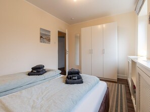 A hotel room with two beds, a wardrobe, a desk, and a mirror. - Ferienhaus in St. Peter-ording (St. Peter-Ording)