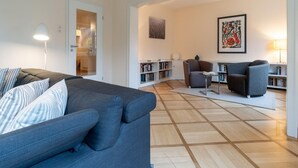 Una sala de estar moderna con un sofá, sillones, una mesa de centro y una estantería.