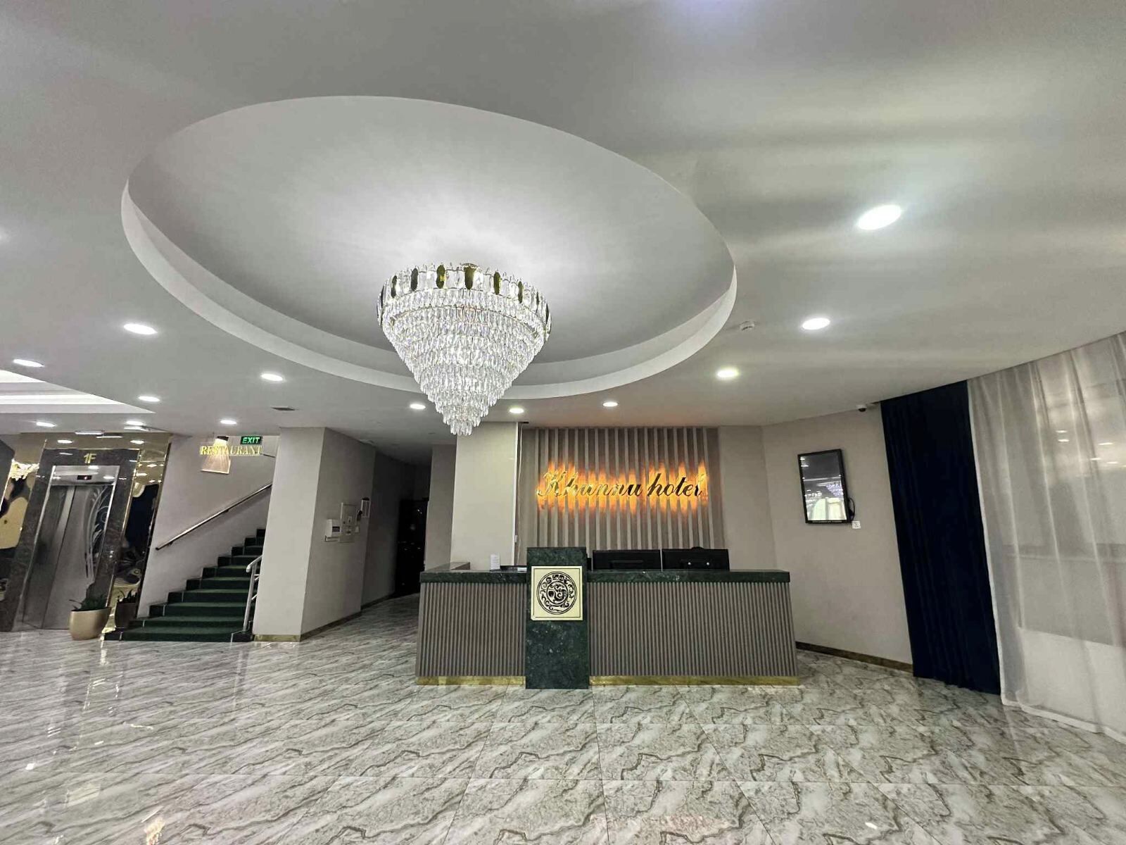A hotel reception area with a marble floor, a chandelier, a reception desk, and a sign that reads "Kansui Hotel".