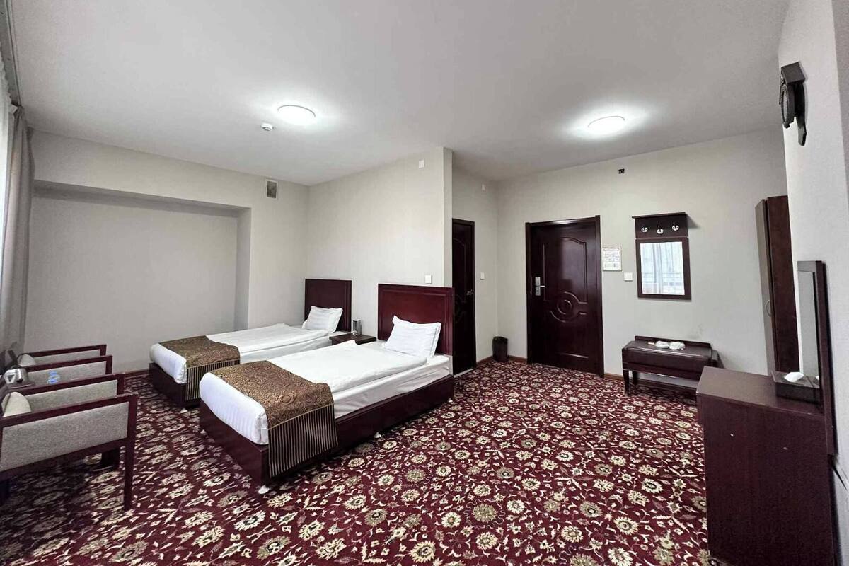 Een hotelkamer met twee bedden, een bureau, een stoel, een kledingkast en een vloerbedekking.
