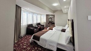 Une chambre d’hôtel avec deux lits, un bureau, des chaises, un miroir et une fenêtre avec des rideaux.