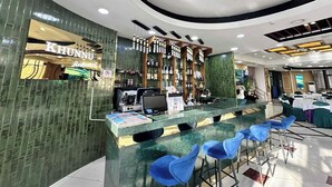 Un espace bar avec un comptoir, des tabourets de bar bleus et une étagère où sont exposées des bouteilles d’alcool.