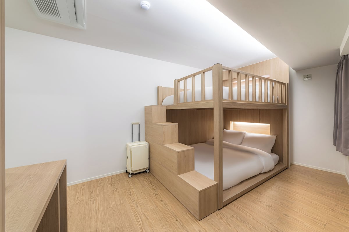 Habitación con literas, una maleta y un escritorio.