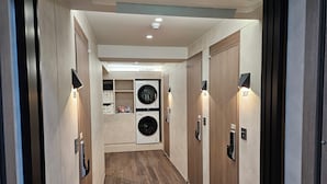 A modern laundry room with two washing machines, numbered 301 and 302, and a shelf with folded towels. - Hi Stay Myeongdong (Seoul)
