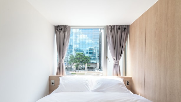 A modern hotel room with a large window, a wooden headboard, and a neatly made bed. - Hi Stay Myeongdong (Seoul)