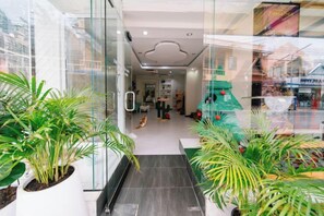 A hotel corridor with glass walls, potted plants, and a staircase leading to an upper level. - Catnip Seaside Hotel&Cafe (Phuket)