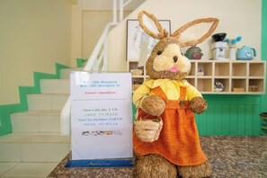 Um coelho de pelúcia em uma bancada com um aviso mostrando a senha do Wi-Fi e o horário de check-in.