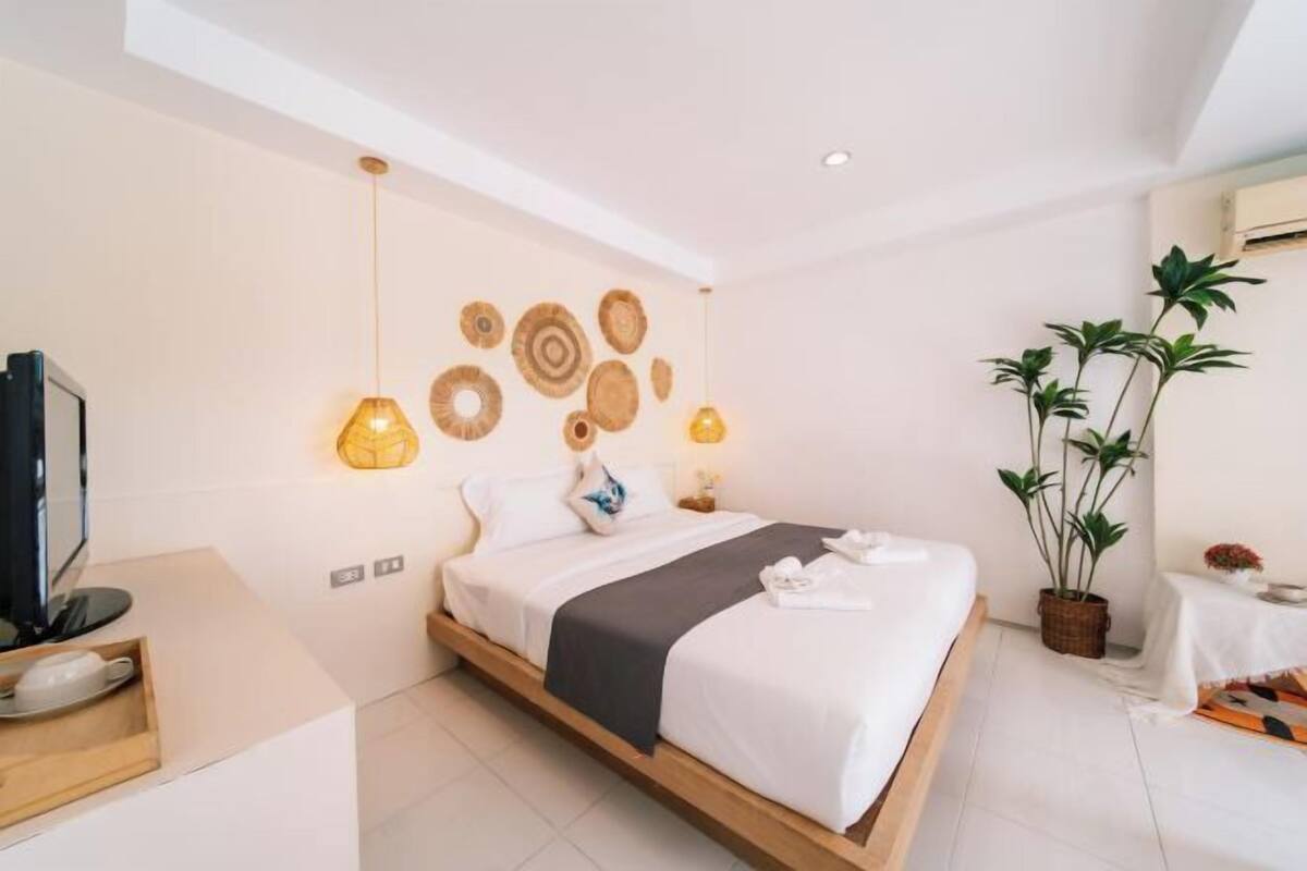 A modern bedroom with a wooden bed, a television, a bedside table, and decorative wall art.