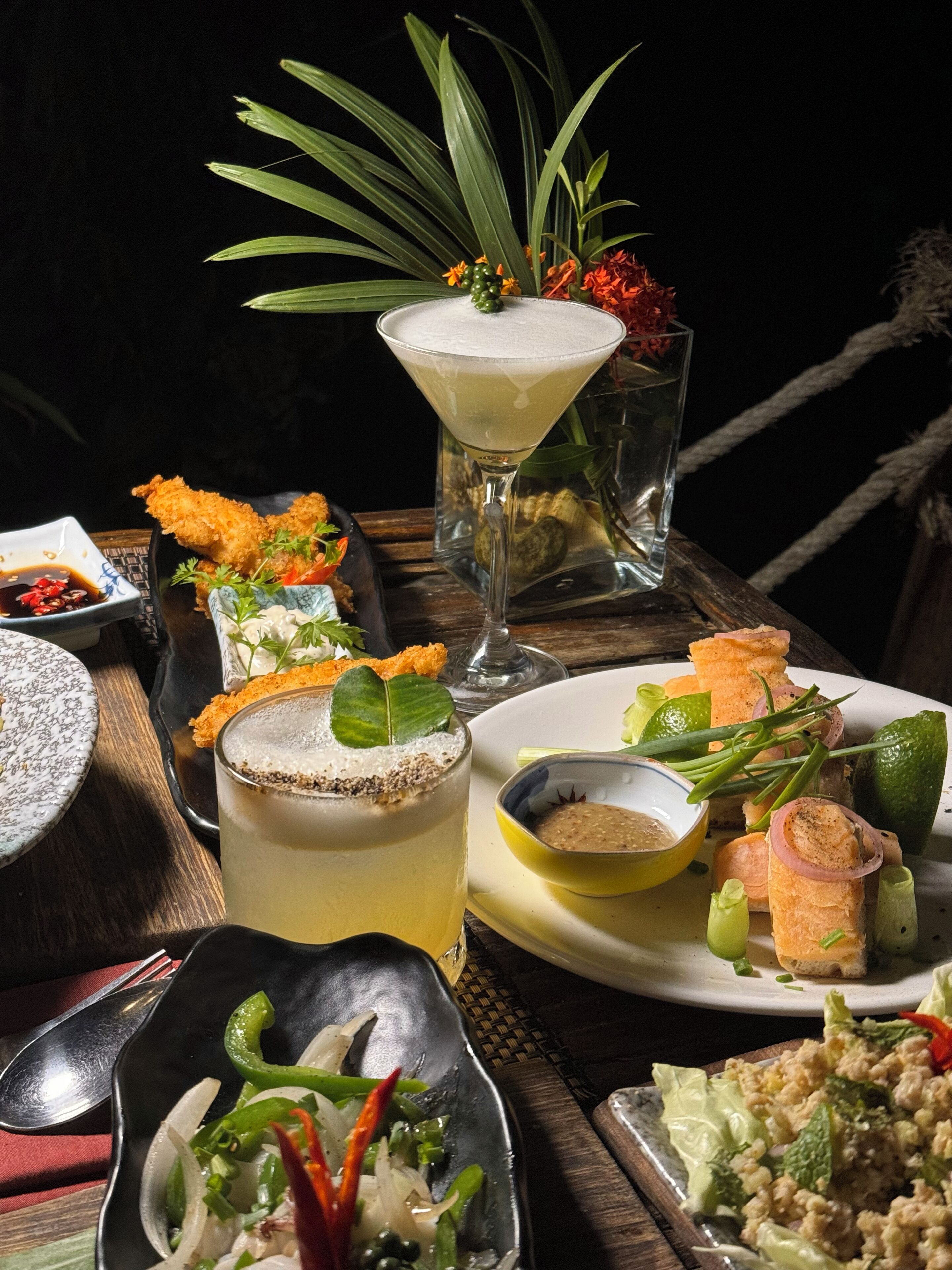 A table set with various dishes, including a martini glass, a cocktail, and several plates of food.