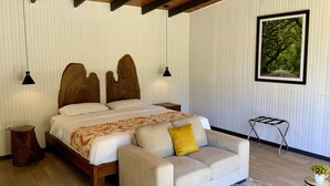 Un dormitorio con una cama de madera, un sofá, una mesita pequeña y un cuadro en la pared.