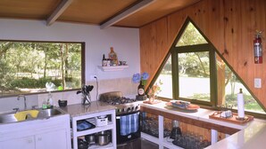 Cocina con detalles de madera, estufa, lavamanos y ventana con vistas a la vegetación.