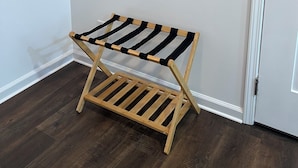 Un banco de madera con correas negras, un perchero con cuatro ganchos y una puerta blanca.