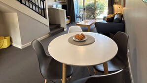 Una sala de estar moderna con comedor, una escalera y vistas al exterior.