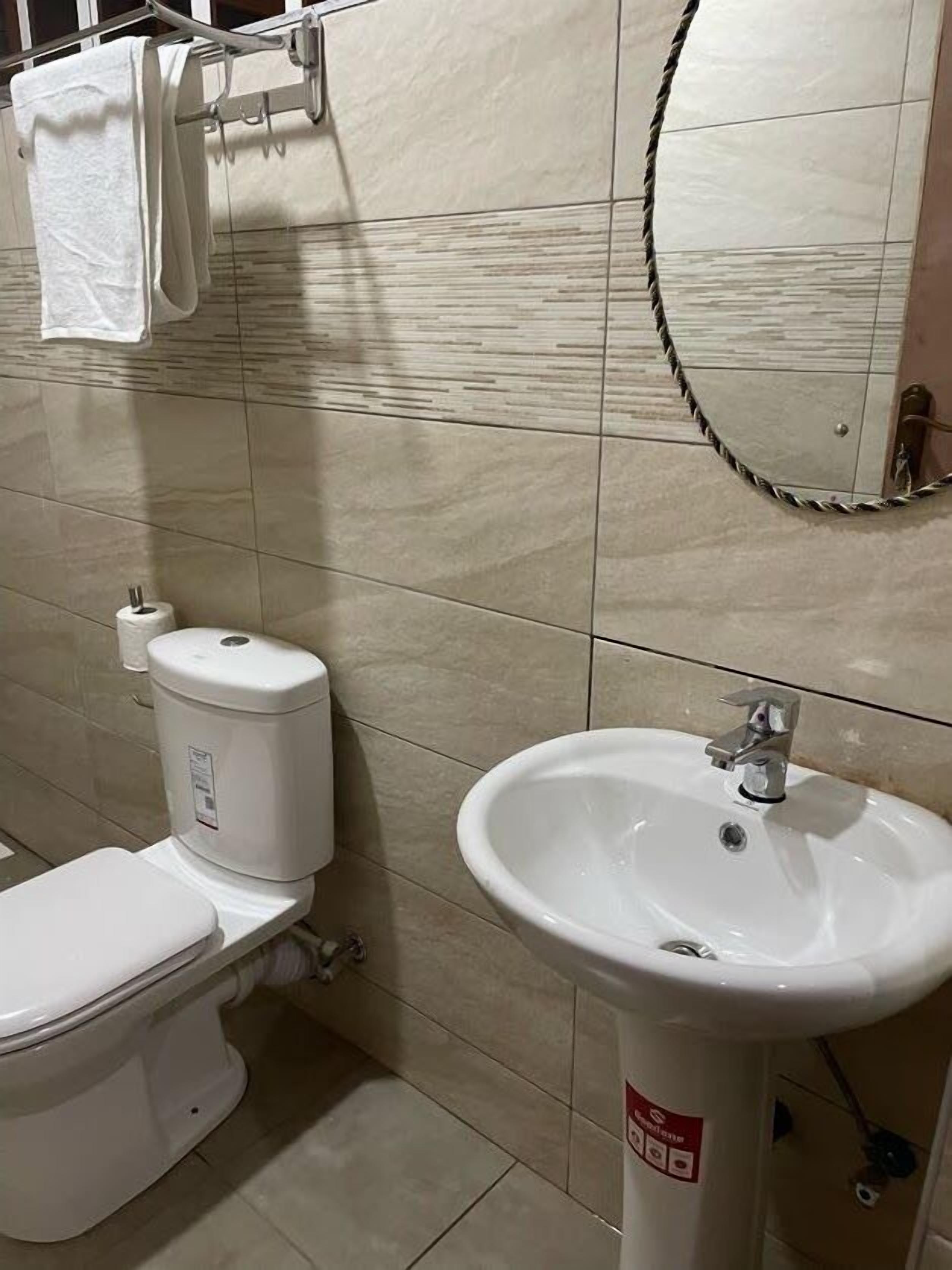 Une salle de bain équipée de toilettes, d’un lavabo et d’un porte-serviettes.