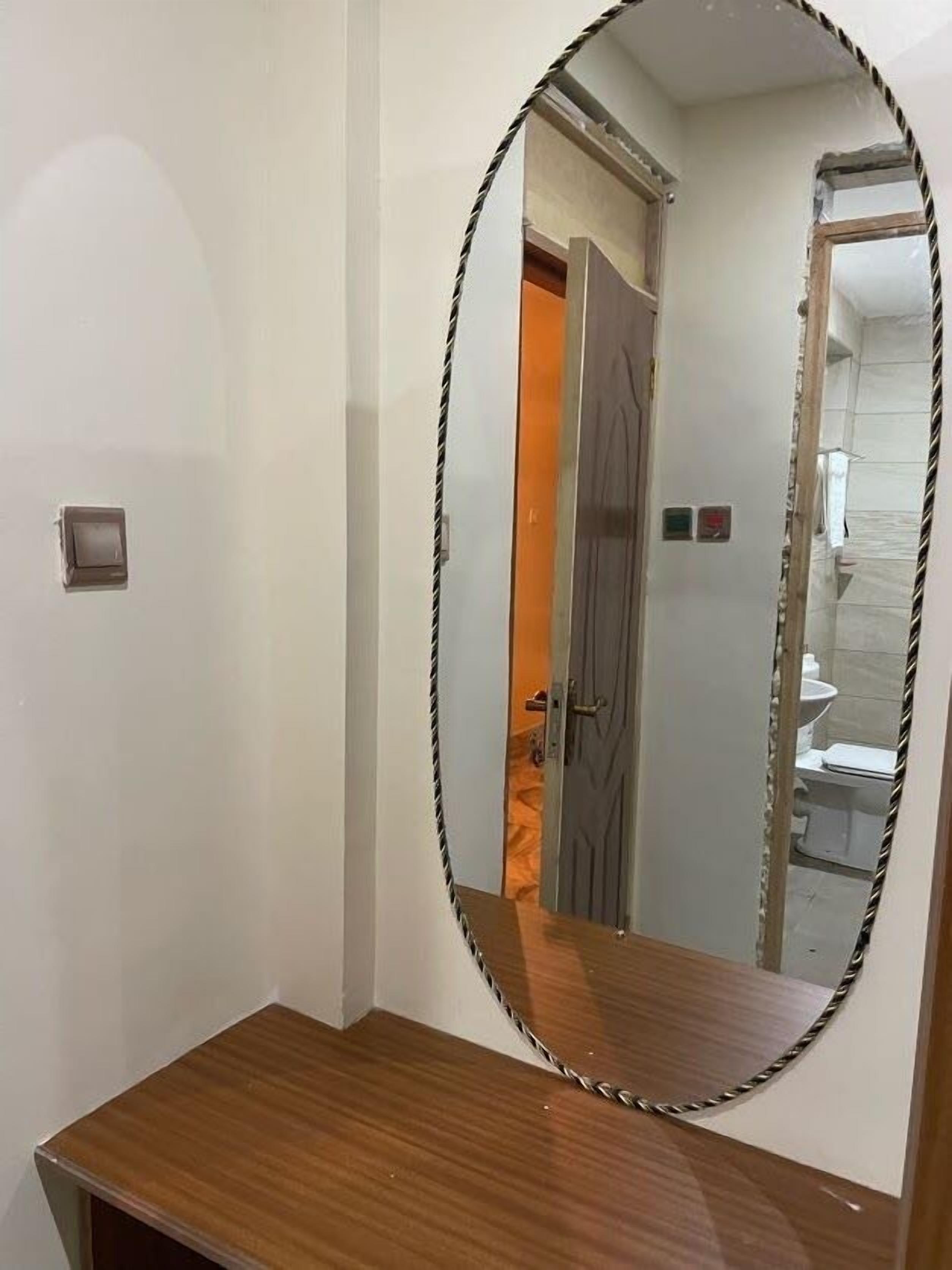 A bathroom with a wooden vanity, a mirror, and a toilet visible through an open door.