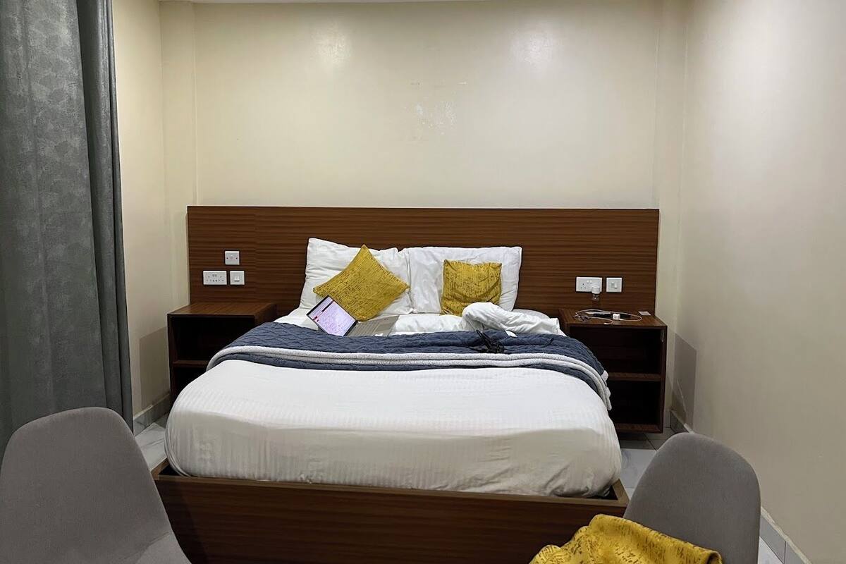 A neatly made bed with a wooden headboard, two bedside tables, and a chair.