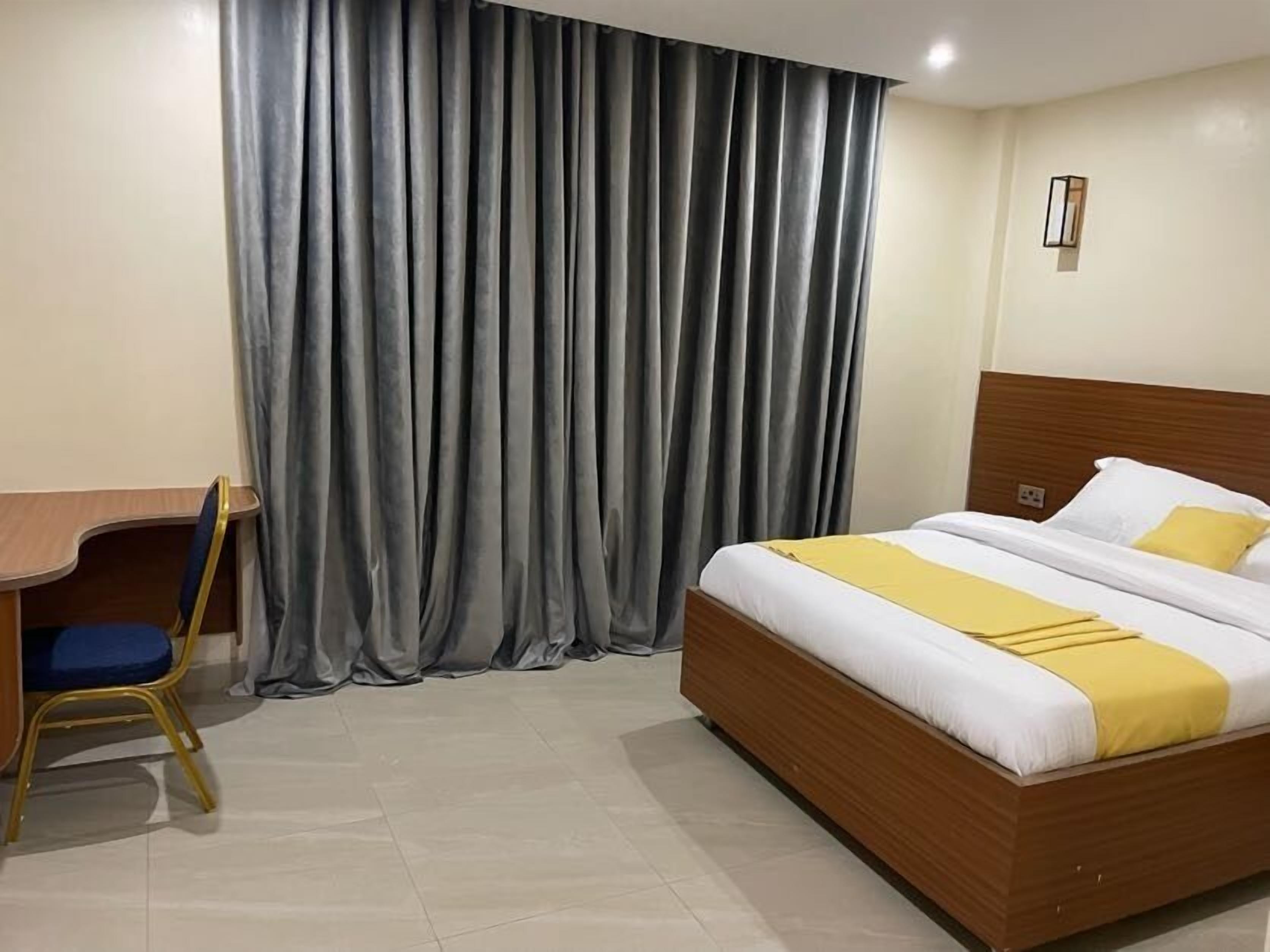 A hotel room with a wooden bed, a desk, and a chair.