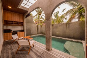 A pool area with wooden deck, lounge chairs, and a kitchen area with wooden cabinets. - Subu Utamas Villas (Payangan)