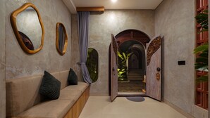 A hallway with a sofa, two mirrors, a curtain, and an open door leading to a staircase. - Subu Utamas Villas (Payangan)
