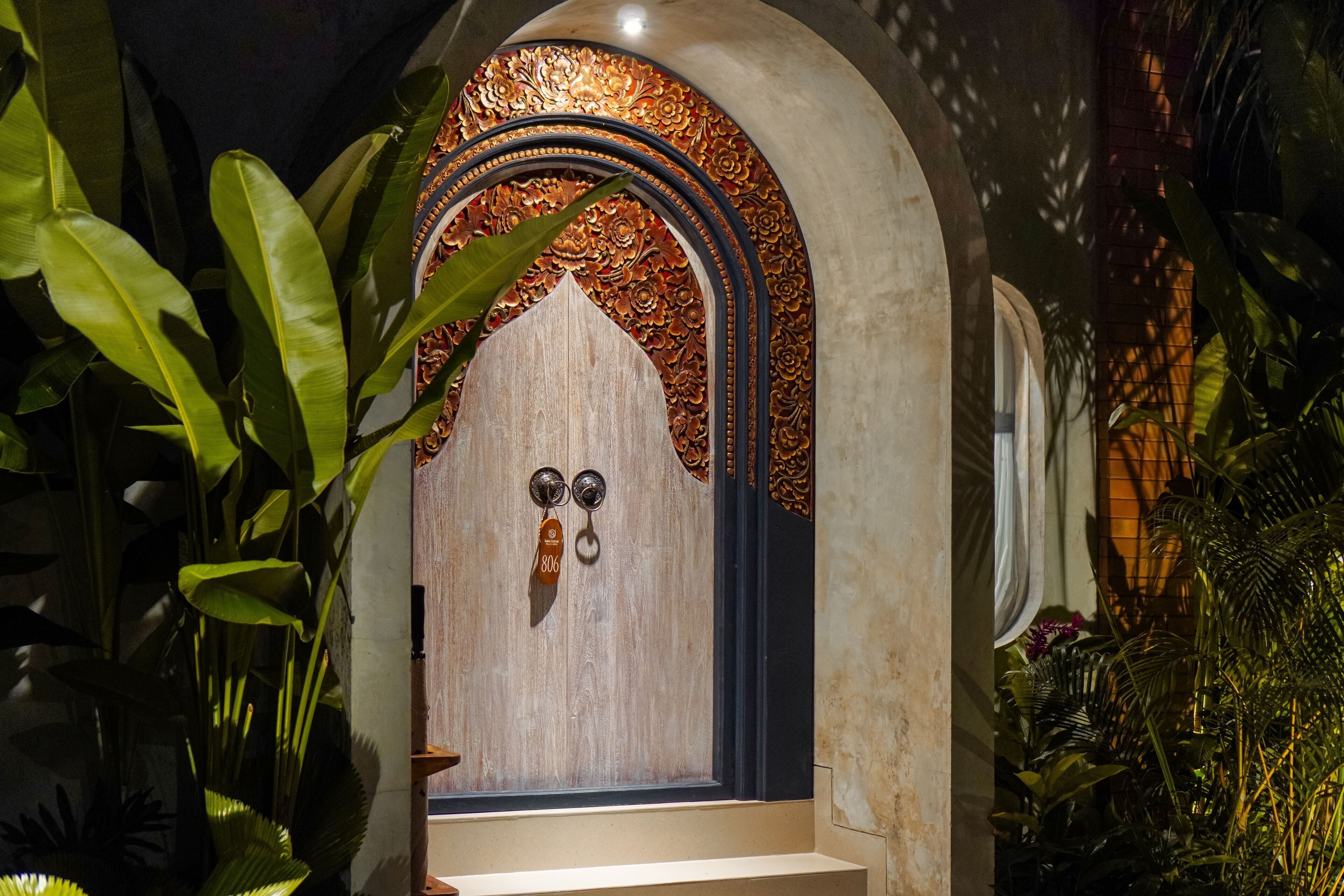 Una porta in legno con un arco decorativo, un maniglia in metallo e una piccola targa con il numero 806.