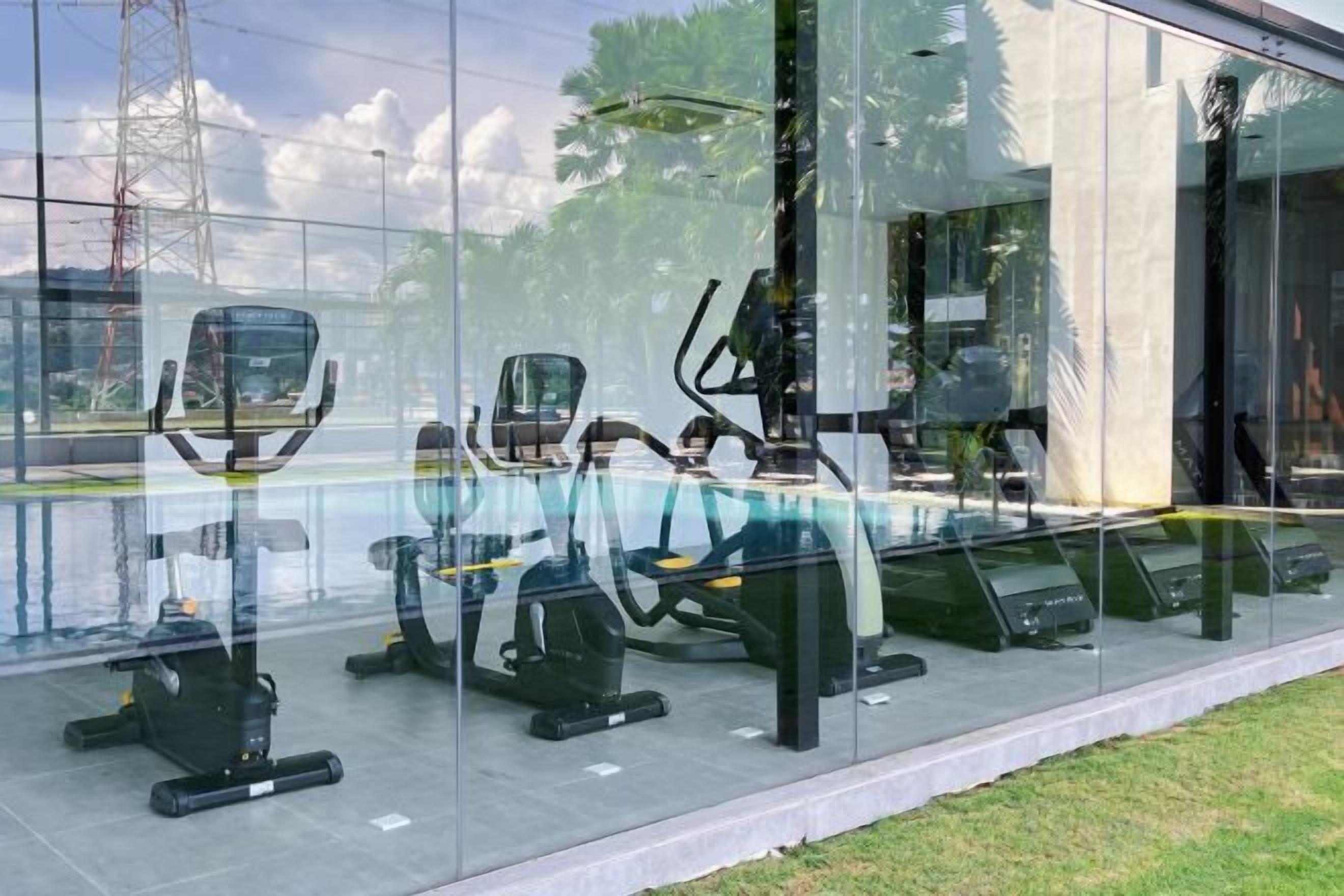 Ett gym med träningsutrustning, inklusive löpband och motionscyklar, som syns genom en glasvägg.