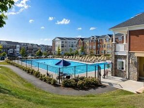A swimming pool surrounded by lounge chairs and a stone building. - Charming 3 bedroom, 3.5 bathroom Townhome In Ashburn, Virginia (Ashburn)