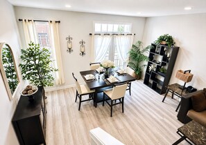 A modern dining area with a table set for four, surrounded by chairs, a bookshelf, and a potted plant. - Charming 3 bedroom, 3.5 bathroom Townhome In Ashburn, Virginia (Ashburn)