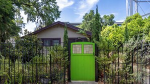 A house with a green front door, surrounded by a black metal fence and various plants. - Luxury Retreat Just Steps from UF Main Campus (Gainesville)