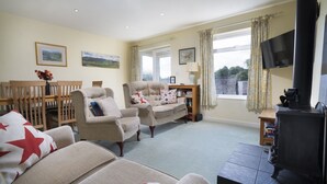 A cozy living room with a sofa, armchairs, a small table, and a fireplace. - 22 Thrang Brow -  3 Bedroom Holiday Home - Langdale Valley (Chapel Stile)