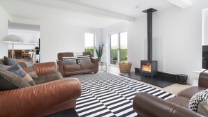 Ein modernes Wohnzimmer mit Ledersofas, einem schwarz-weißen StreifenTeppich und einem Kaminofen.