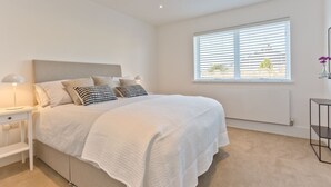 Ein Schlafzimmer mit Bett, Nachttischen, einem Fenster mit Jalousien und einer Heizung.